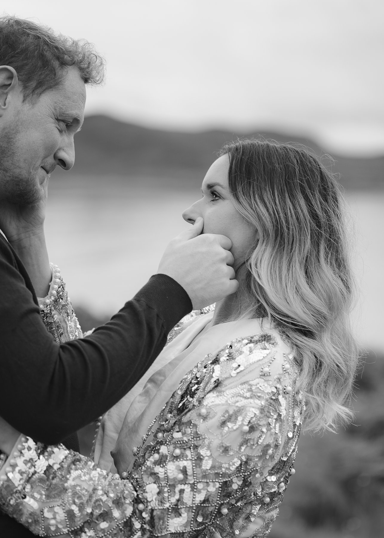 Intimate close up of couple gazing at each other, man gently touching woman's face outdoors