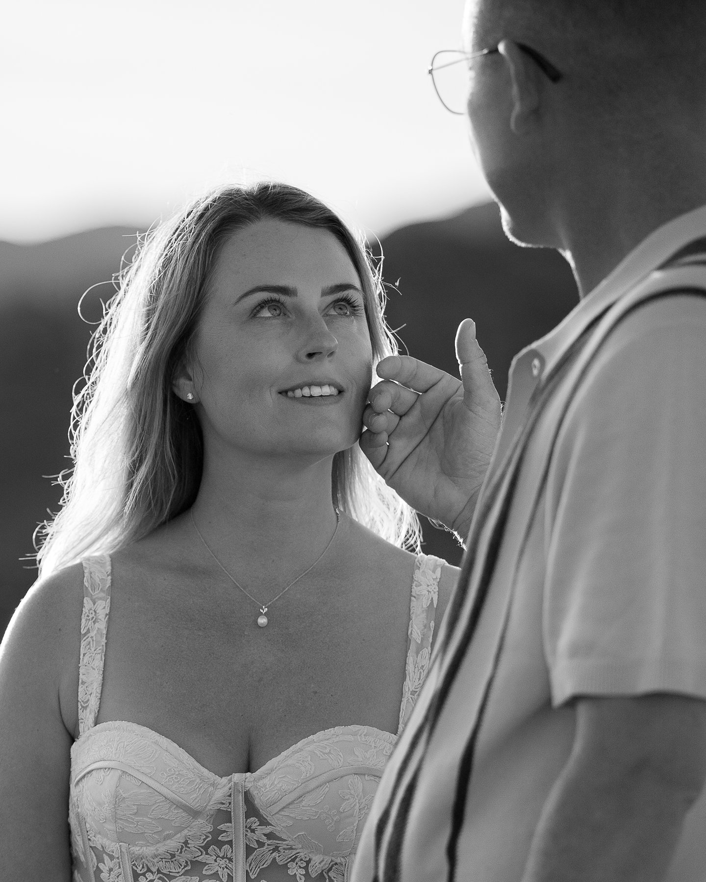 Groom gently touching bride's face as she smiles up at him lovingly.